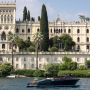 Riva Aquariva cruising on Lake Garda with Isola del Garda and its neo-Gothic villa in the background.