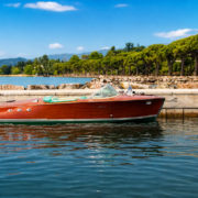 Vintage Riva boat on Lake Garda with elegant shoreline and crystal clear water, luxury private boat rental experience